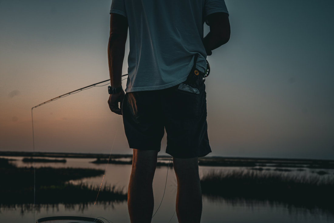 Silhouette of a fisherman at golden hour on the water